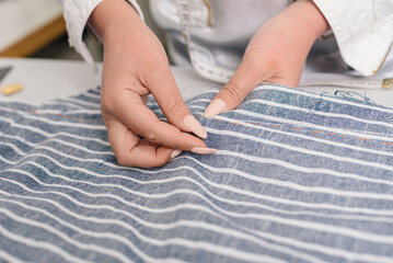 Professional seamstress hands basting and sewing in modern atelier