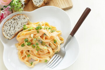 Italian food, cream sauce and spring onion fettuccine pasta on white plate 