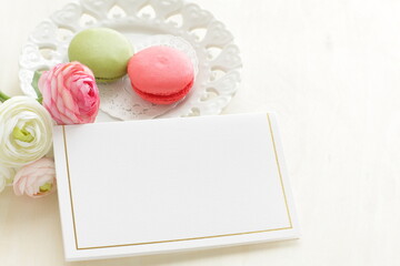 pink and green tea color macaron on white dish with flower and blank greeting card for background image