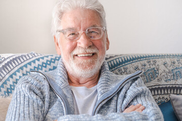 Fototapeta Portrait of happy bearded senior man relaxing on sofa at home looking at camera smiling. Headshot of elderly attractive man enjoying retirement. obraz