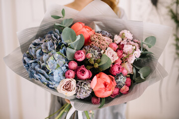 Very nice young woman holding big and beautiful bouquet of fresh hydrangea, roses, peony, carnations, eucalyptus, matthiola in colors, cropped photo, bouquet close up - 507767588