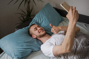 A guy lying in bed taking selfies