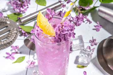 Lilac drink. Alternative organic natural cocktail or mocktail, infused drink from lilac flowers. Lilac lemonade with ice in a tall long glass.