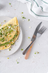 Nice breakfast with avocado. Omelet with microgreens. Gray background with breakfast.