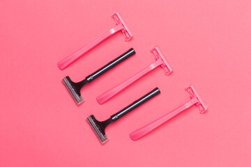 Skin Care Ideas. Flatlay Upper View Image of Five Colorful Pink and Black Disposable Razors Shavers Placed Reversed Over Trendy Pink Coral Background.