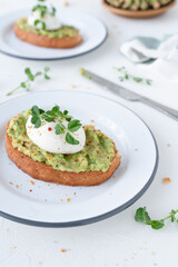 Beautiful breakfast with avocado and poached egg. Pea microgreens. Gray background with breakfast