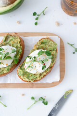 Beautiful breakfast with avocado and poached egg. Pea microgreens. Gray background with breakfast