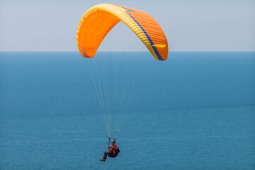 Orange paraglider against the background of the blue sea. Close-up.