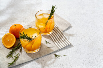 Summer refreshing cocktails with rosemary and orange juice on a light background. Hard seltzer, lemonade, refreshing drinks.  Copy space