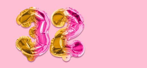 Rainbow foil balloon number, digit thirty two on a pink background. Birthday greeting card with inscription 32. Top view. Numerical digit. Celebration event, template. Banner