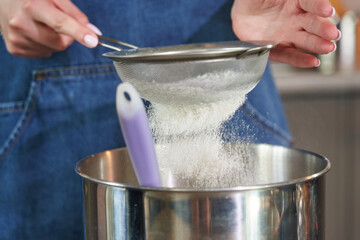 female hands sift flour through a sieve close-up