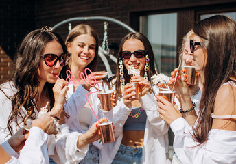 Happy and cheerful group of women friends together dancing and drink champagne on the rooftop at...