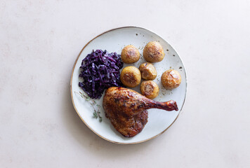 Baked duck leg with potatoes and red cabbage.
