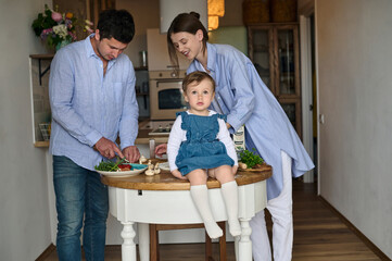 dad mom and their daughter cook pizza together in the kitchen. T