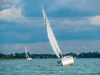 Obraz premium sailing yacht or sailboat on full sails swims on a lake in a windy day