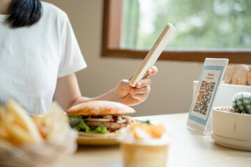 Women use phone to scan qr code to select food menu and collect points. Scan to get discounts or pay for food. The concept of using a phone to transfer money or paying money online without cash.