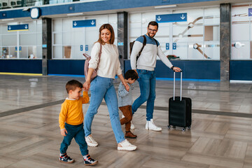 Happy young family with luggage in railroad station go together on vacation.