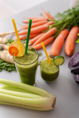 Green smoothies in glass with straw and cucumber and vegetagbles at background, detox, vegan, vegetarian healthy vegetable drink