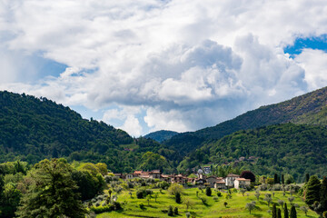 Fototapeta na wymiar Village among green hills on the slopes of the Italian Alps not far from Lake Como, photo taken in spring. Picturesque landscape