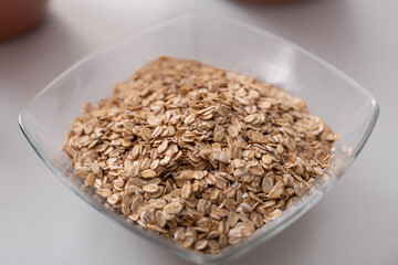 Glass bowl of oat flakes on white kitchen counter