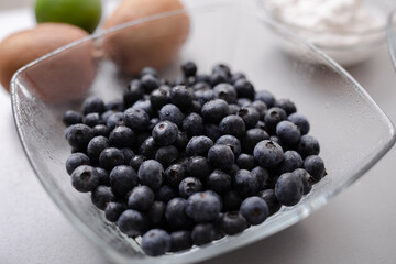 Fresh blueberries in glass bowl on kitchen counter, healthy food for diet.