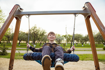 Happy child boy on swing. Little kid playing in the summer pack