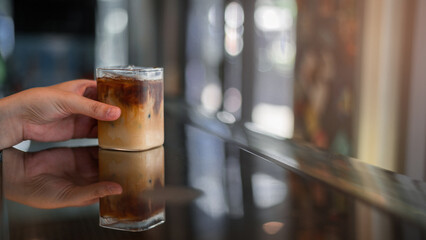 Ice coffee on a table with cream being poured into it showing the texture and refreshing look of the drink