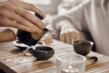 A close-up shot of a Chinese tea ceremony. On the table there is a gaiwan, bowls, a tea keeper and...