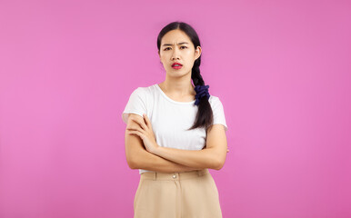 Fototapeta premium Asian woman in white shirt posing arms crossed and feeling upset on the pink screen background.