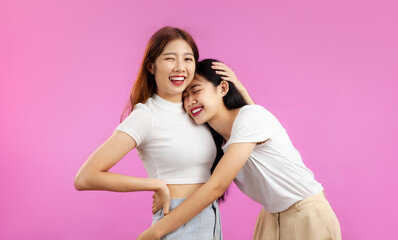 Happy lgbt couple lesbian in white t-shirt isolated on pink color background. Asian women Pride month concept.