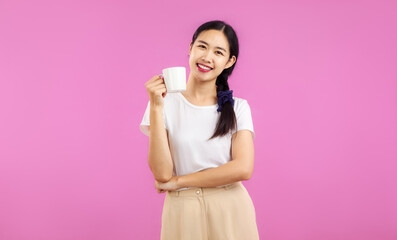 portrait of a pretty asian woman with a cup isolated on pink background