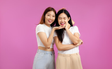 Young two asian women long hair in white tank top and t-shirt posing in concept of LGBTQ couple on the pink screen background.