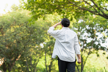 back view of an asian young man holding a book in the park 