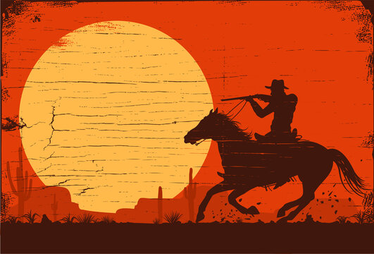 Silhouette cowboy riding a horse carrying a gun at sunset.