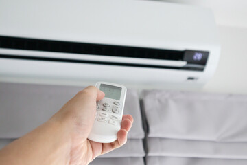 Hand with remote control directed on air conditioner