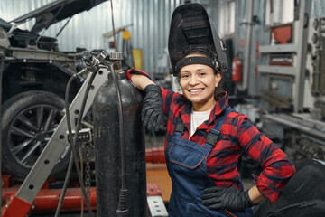 Cheerful woman auto mechanic standing in vehicle repair shop