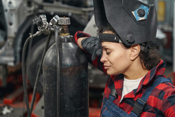 Fototapeta na wymiar Woman auto mechanic standing near gas cylinder in garage