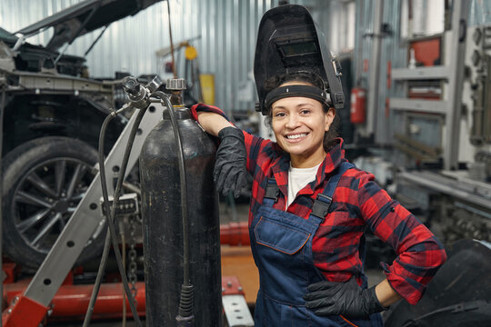 Cheerful woman auto mechanic standing in vehicle repair shop