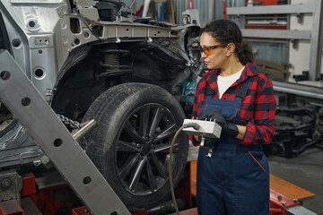 Obraz na płótnie Canvas Female mechanic using diagnostic equipment in auto repair shop