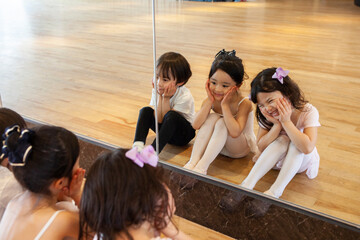 鏡にむかってかわいい顔をしているバレエダンサーの幼い子供達