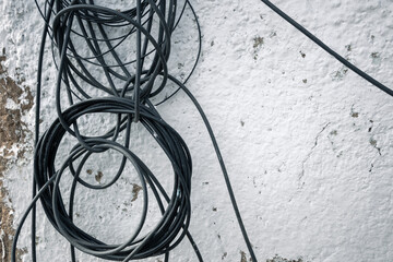 Tangled wires on the background of a white clay wall