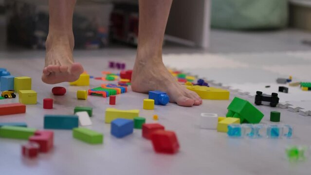 father walks among the mess in the children's room, trying not to step on those toys. parent on maternity leave. rubbish at home. decluttering concept.