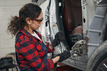 Woman auto mechanic working at car repair service station