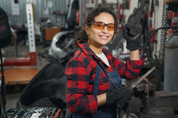 Fototapeta na wymiar Cheerful woman auto mechanic working in car repair shop