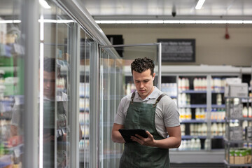 Employee of a food market stock taking with a digital tablet