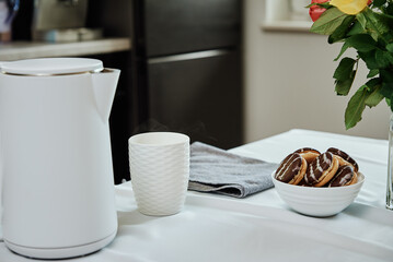 Tea time, Electric kettle with boiled water and cup for preparing tea on table, Morning breakfast at kitchen