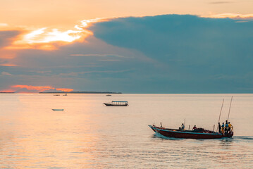 Fototapeta na wymiar Fishing boat with fisherman return home, Indian ocean on a scenic sunset. Zanzibar, Tanzania