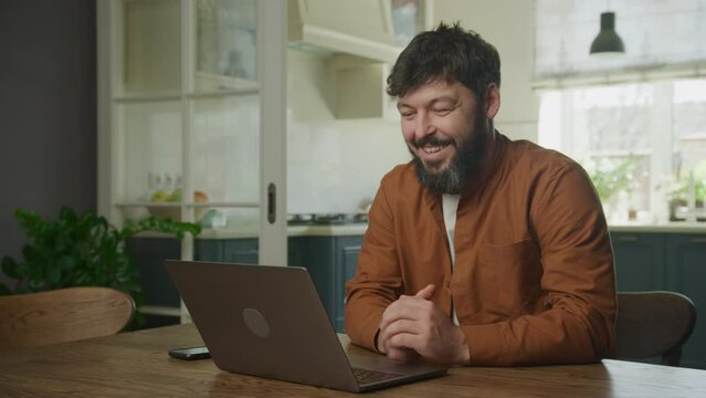 Young adult caucasian bearded entrepreneur recieving good news on his laptop
