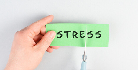 The word stress is standing on a paper, cutting the word with scissors, burnout concept, work life...
