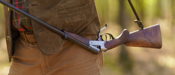Fototapeta na wymiar Close-up of hunter man carrying his rifle gun in forest.